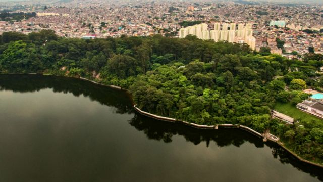 Represa margeada por floresta com moradias nos arredores