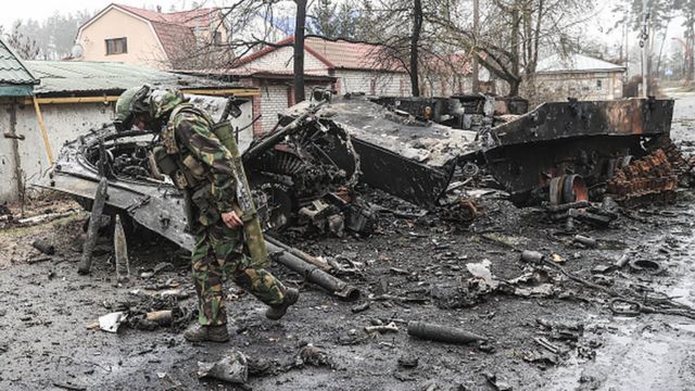 Украинский военный осматривает сгоревшую российскую технику