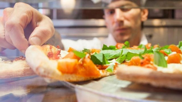 Un chef manipulando una pizza