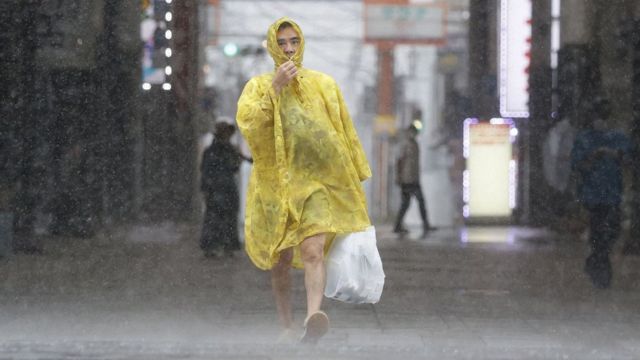A Japanese man in a raincoat walking in the rain