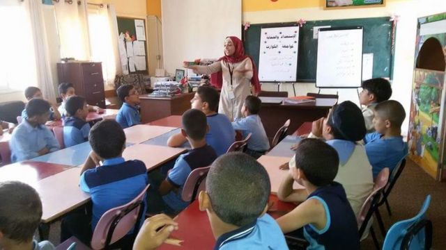 Ola Abu Hasaballah conversando com crianças em uma sala de aula