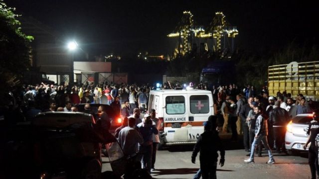 لبنانيون يتابعون تحرك سيارة إسعاف خارج ميناء طرابلس