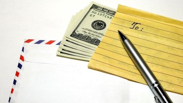 Envelope, US currency, notepaper and a pen