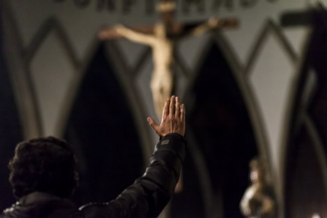 Hombre frente a Cristo levantando la mano