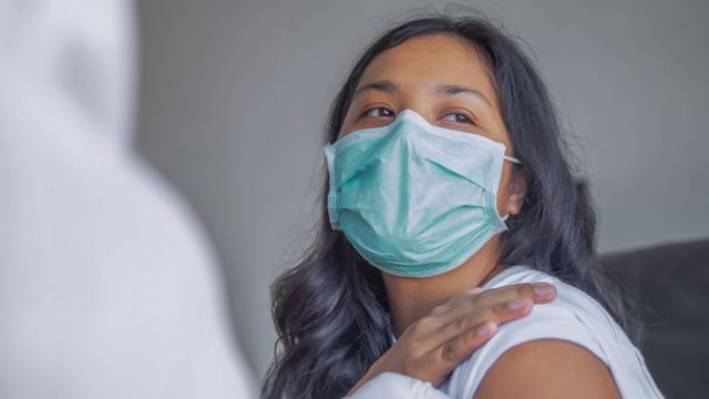 Woman rolls us up her sleeve for the vaccine