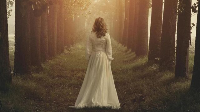 Mulher com vestido branco em meio a floresta