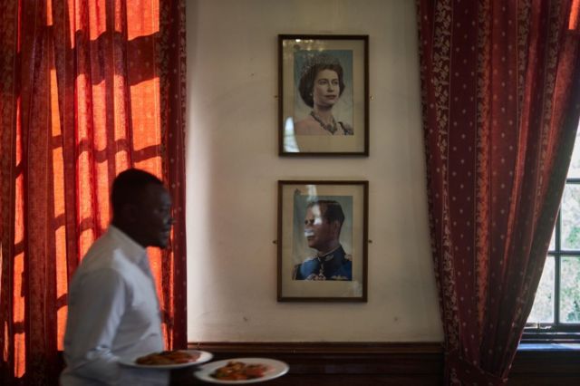 Un camarero lleva el desayuno frente a un retrato de la reina Isabel II en el comedor del Club Bulawayo el 9 de septiembre de 2022 en Bulawayo, Zimbabue. Originalmente un club de caballeros, con paredes que mostraban una gran colección de dignatarios británicos y soldados de Rhodesia, la única mujer permitida era la reina Isabel II.