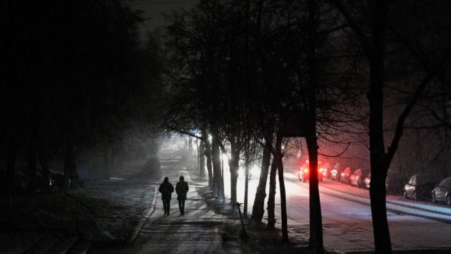 Deux personnes marchent dans une rue de Kyiv pendant une panne de courant