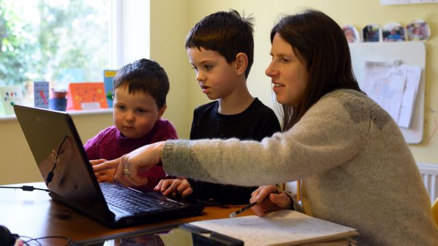 Madre e hijos frente a la computadora.