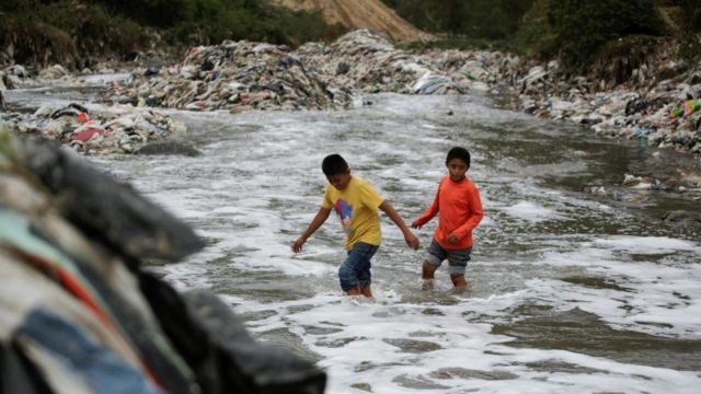 Dos niños cruzan las aguas turbias del contaminado rio Las Vacas