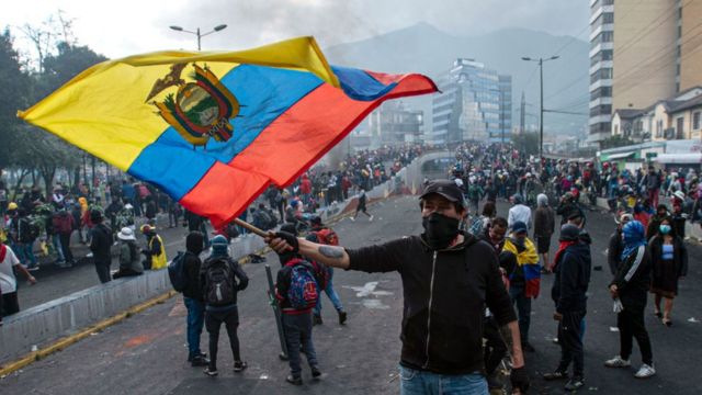 Un manifestante enmascarado ondea una bandera de Ecuador durante el décimo día de protestas contra el presidente Guillermo Lasso el 22 de junio de 2022 en Quito, Ecuador. Los manifestantes exigen reformas sociales y económicas en medio del aumento de la inflación, el desempleo, la pobreza y la desigualdad.