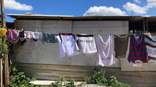 Roupas penduradas em frente a barraco de madeira
