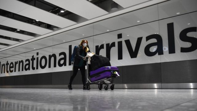 A passenger pushes luggage through the Arrival Hall of Terminal 5 at London"s Heathrow Airport