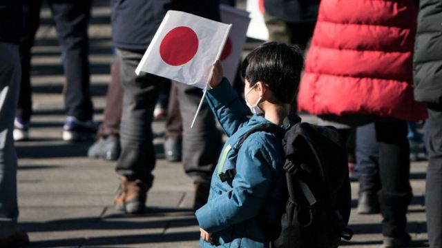 A boy holds a flag of Japan