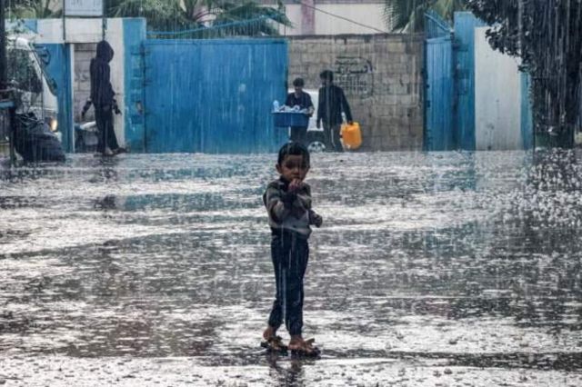 雨の中たたずむ幼い男の子（ガザ地区南部）