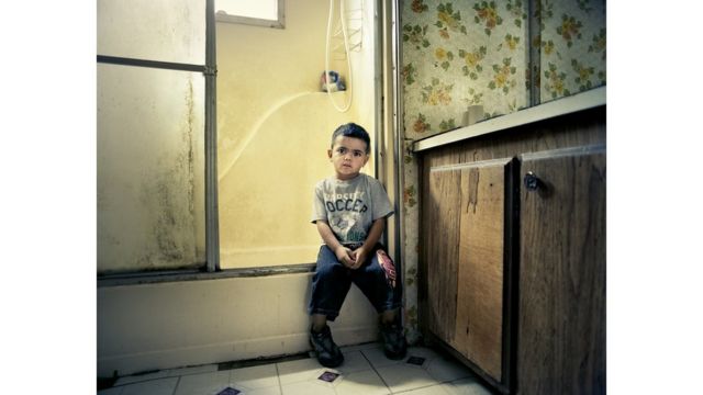 Niño sentado en el borde de una ducha.
