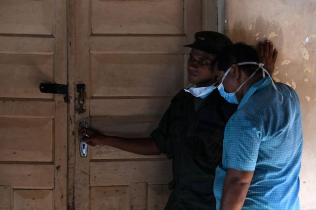 Sri Lankan hospital workers stand at the door to a morgue following a blast in a church in Batticaloa