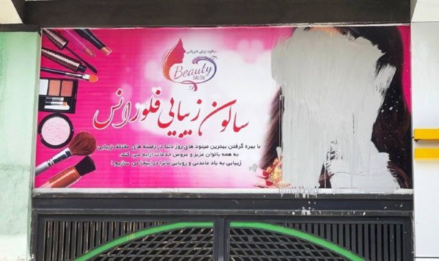 Um cartaz no Afeganistão em que o rosto de uma mulher foi riscado