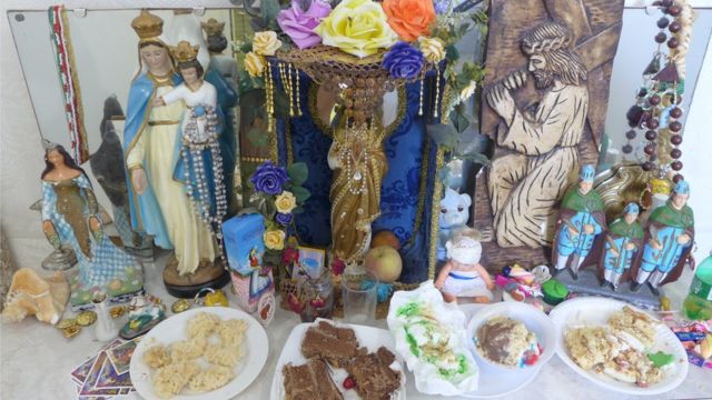 Sincretismo religioso em um pequeno altar mantido com oferendas na casa