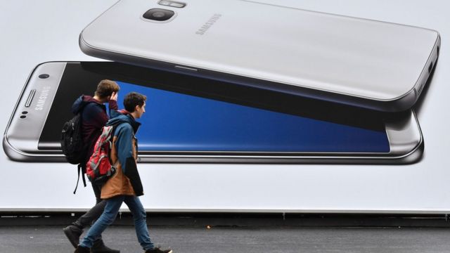 Dos jóvenes pasan frente a una propaganda de Samsung