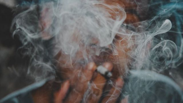 Homem fumando com fumaça em frente ao seu rosto