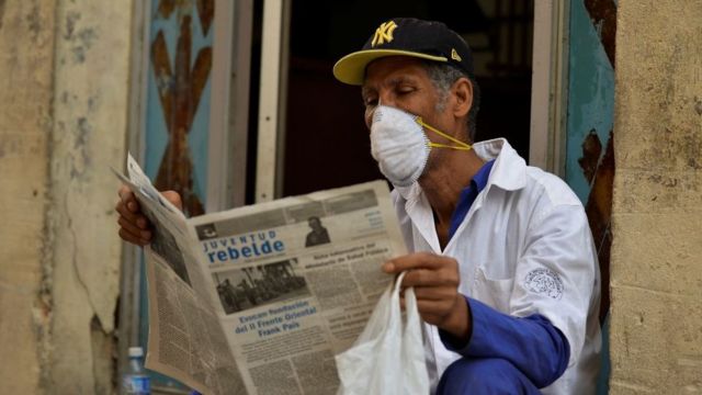 Hombre con máscara lee un diario en La Habana