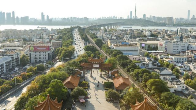 Vista aérea de Wuhuan durante o dia, onde se vê uma ponte, prédios e um portal tradicional chinês