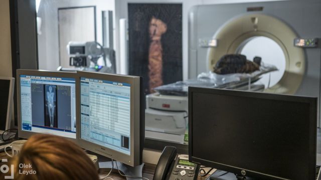Uma múmia é vista passando por um tomógrafo enquanto os cientistas examinam as imagens