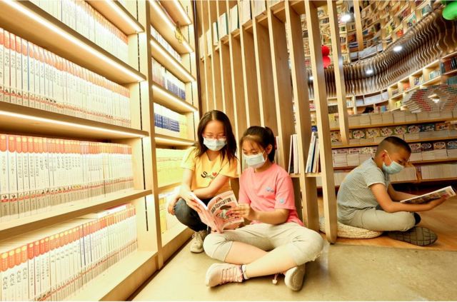 Three elementary school students read in the bookstore to welcome the International Children's Day.