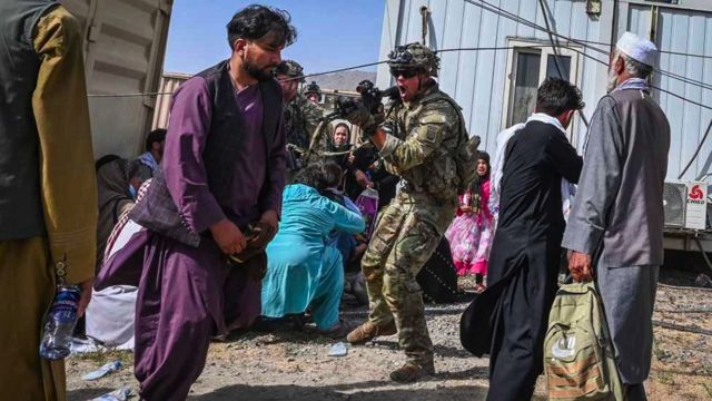 A US soldier points his gun towards an Afghan passenger at the Kabul airport in Kabul