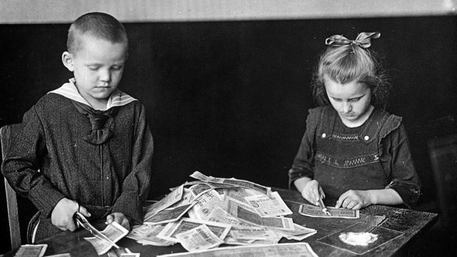 Niños alemanes destruyen con tijeras los billetes que ya no tenían valor.