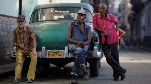 Tres hombres sobre un carro en La Habana.