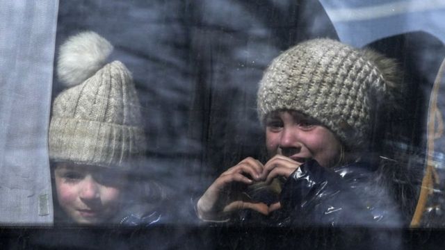 ۲۴ مارس ۲۰۲۲ غیرنظامیان از مسیرهای بشردوستانه، شهر ماریوپل اوکراین، منطقه تحت کنترل ارتش روسیه و جدایی‌طلبان طرفدار روسیه تخلیه می‌شوند، یک دختر کوچک با دستان خود شکل قلب می‌سازد