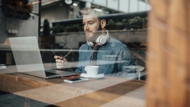 Un joven trabajando con su laptop en un café