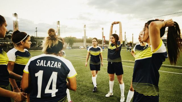 Sekelompok wanita bermain sepak bola.
