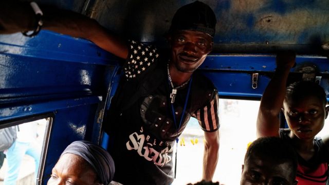 A passenger stands as another sits, holding on to the inside roofline of the taxi-van as they ride to their destinations of Limete Municipality in Kinshasa, Democratic Republic of Congo, September 12, 2017