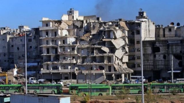 حافلات تستخدم في عمليات الإجلاء تقف وسط الدمار في شرق حلب