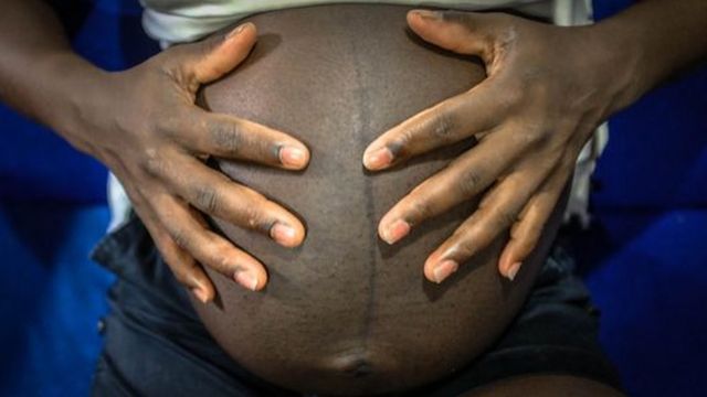 Une jeune femme enceinte touche son gros ventre