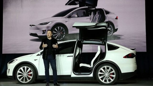 Elon Musk, delante de un coche blanco de Tesla