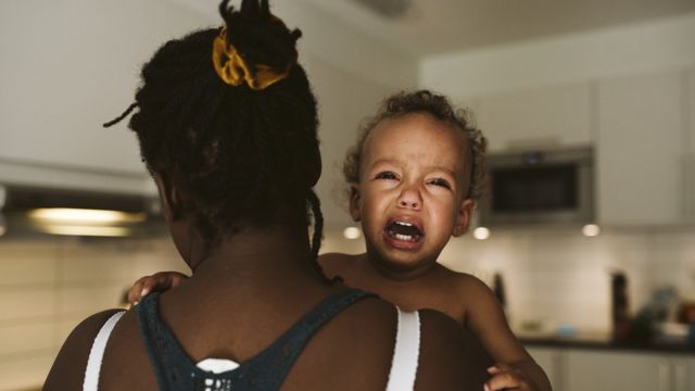 Madre carga niño llorando.