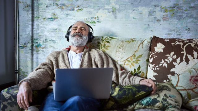 Hombre con su laptop escuchando musica.