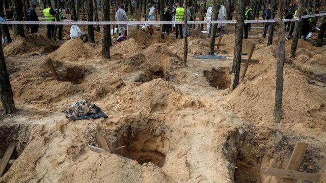 Police and experts work at a place of mass burial during an exhumation in Izyum, 17 September 2022.