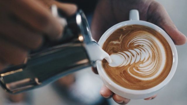 Taza de latte con diseños hechos con el café sobre la leche