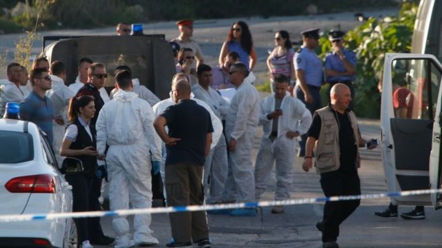 Police and forensics experts stand behind a road block after a powerful bomb blew up a car killing investigative journalist Daphne Caruana Galizia in Bidnija, Malta, 16 October 2017