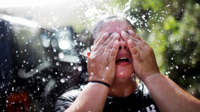 Una mujer en Puerto Rico se refresca luego de llenar recipientes con agua debido a la escasez de este recurso tras el huracán María