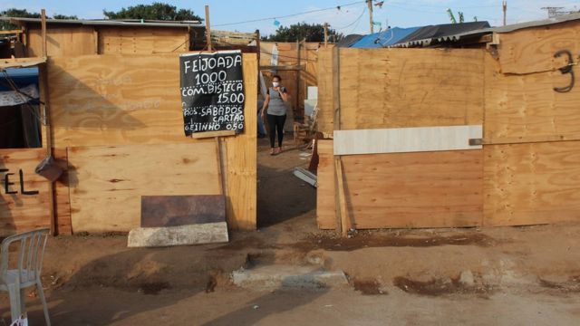 Construção com tapumes de madeira e placa anunciando feijoada a R$10