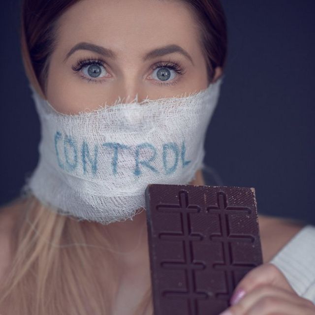 Mujer con tapabocas que dice "control" y un chocolate en la mano