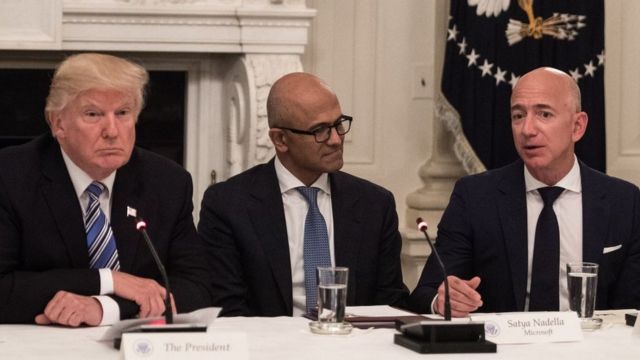 Trump e Bezos sentados em mesa durante evento