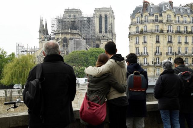 People hug while looking at Notre-Dame