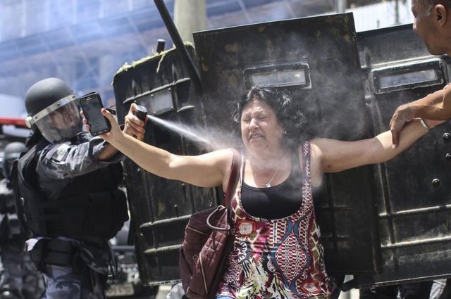Seorang polisi Brasil menyemprotkan gas air mata kepada seorang pengunjuk rasa di Rio de Janeiro,